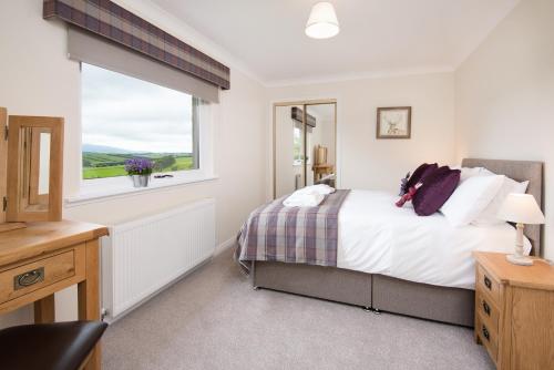 um quarto com uma cama e uma janela em Lammerlaw Farm Cottage em Biggar