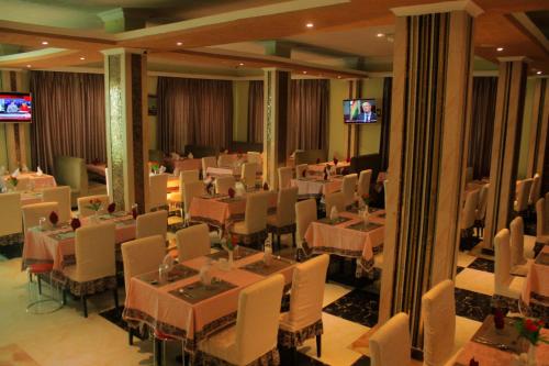 a dining room with tables and chairs and televisions at Tiffany Diamond Hotels - Mtwara in Mtwara