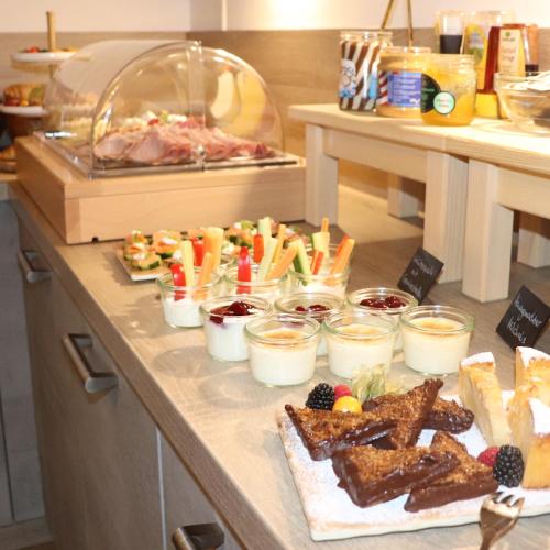 a buffet with various types of food on a counter at Hotel Garni Möwe am See in Prien am Chiemsee