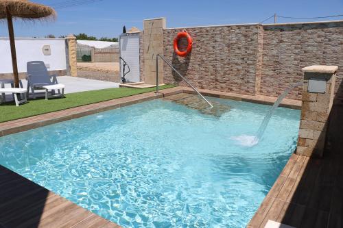 - une piscine avec un préservateur de vie rouge dans une cour dans l'établissement Chalet carril de los pareja, à Conil de la Frontera