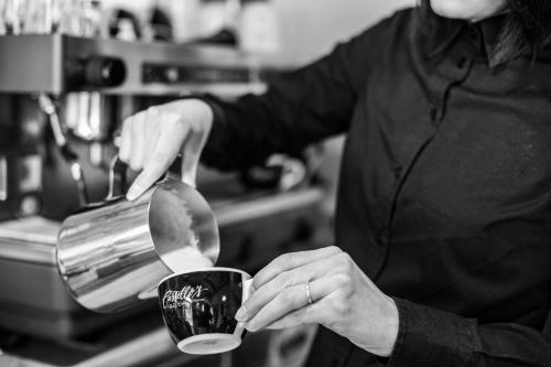a woman is pouring food into a coffee cup at Hotel Il Castello in Certaldo