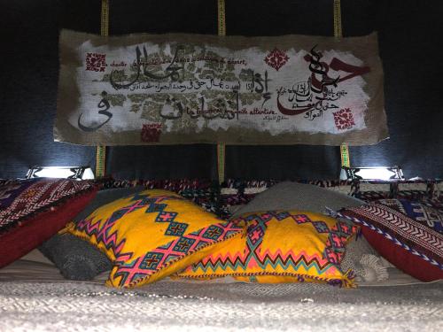 a pile of pillows on a bed with a sign at Majorelle Desert Camp in Zagora