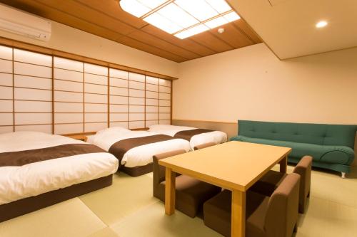 a room with four beds and a table in it at Osaka Riverside Hotel in Osaka