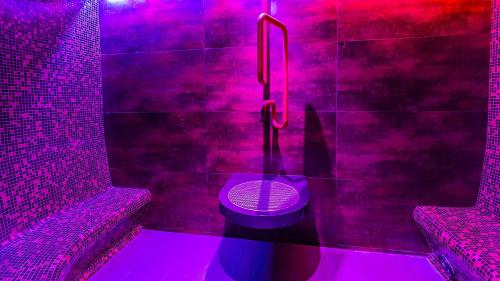 a pink bathroom with a toilet with purple lights at Hotel AquaCity Mountain View in Poprad