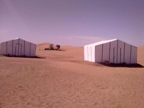 two buildings in the desert with a dirt road at Majorelle Desert Camp in Zagora