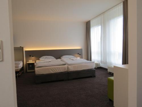 a bedroom with two beds and a large window at Comfor Hotel Ulm City in Ulm