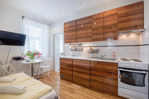 cocina con armarios de madera, fregadero y mesa en Studio - Grandtulipan, en Gdynia