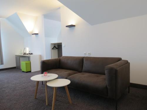 a living room with a brown couch and two tables at Comfor Hotel Ulm City in Ulm