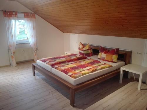 Schlafzimmer mit einem Bett mit Holzdecke in der Unterkunft Obere Ferienwohnung Asshoff zwischen Odenwald, Taubertal und Bauland in Berolzheim