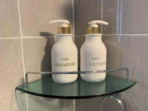two bottles of soap on a glass shelf in a bathroom at Gyeongju Roamers Stay in Gyeongju