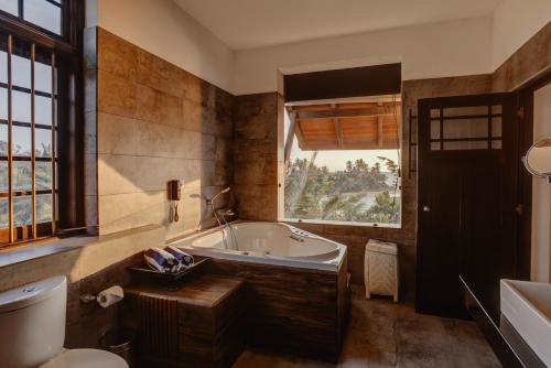 ein Bad mit einer Badewanne, einem WC und einem Fenster in der Unterkunft The Postcard Galle in Galle