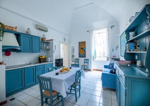 a kitchen with blue cabinets and a table and chairs at La finestra sul borgo in Atrani