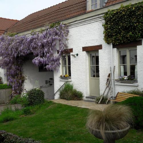 a white house with a wreath of purple flowers at L'Atterrissage in Santes