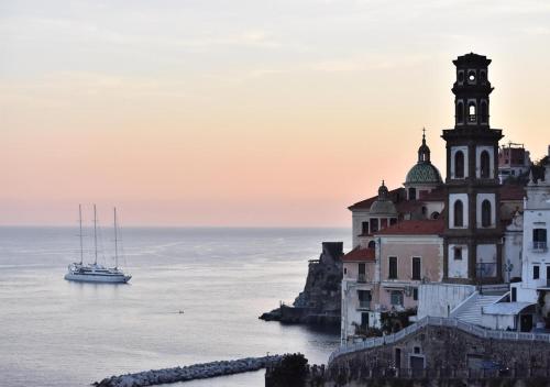 a building on the cliff with a boat in the water at La finestra sul borgo in Atrani