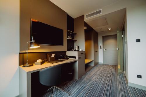 a hotel room with a desk with a monitor on the wall at Hotel Evva in Tarnobrzeg