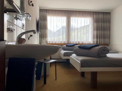 a bathroom with three beds and a sink and a tub at Catrina Lodge in Disentis
