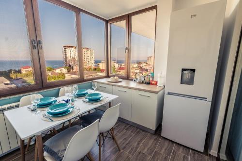 uma cozinha com uma mesa branca, cadeiras e janelas em Luna Apartment em Constança