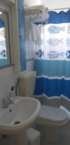 a bathroom with a sink and a toilet and a mirror at Quartos para Ferias in Fuzeta