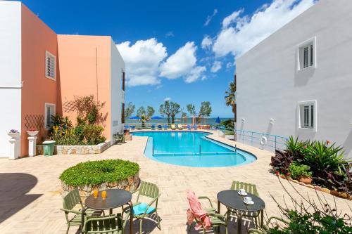 a patio with tables and chairs and a swimming pool at Eden Beach Hotel in Agia Marina Nea Kydonias
