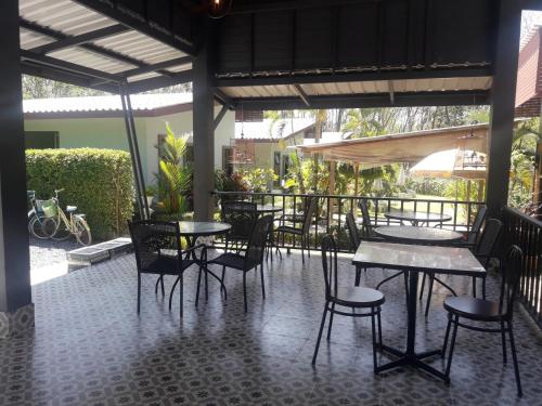 een patio met tafels en stoelen op een tegelvloer bij Phuket Sirinapha Resort in Nai Yang Beach