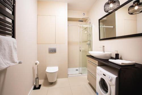 a bathroom with a sink and a washing machine at Apartamenty Silence Baltic Classic in Pobierowo