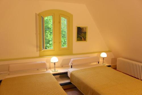 two beds in a room with two windows at Villa Beckmann in Gengenbach