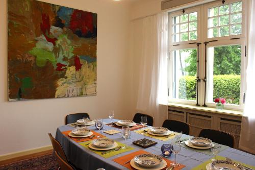 un comedor con una mesa con sillas y una pintura en Villa Beckmann, en Gengenbach