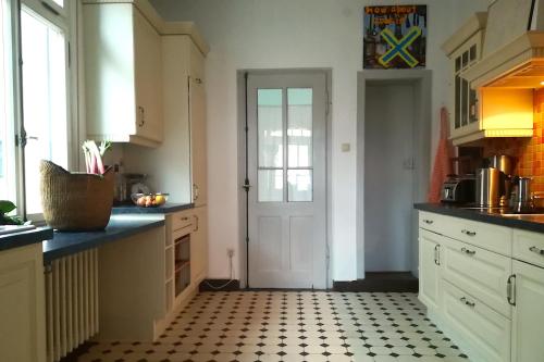 a kitchen with a white door and a black and white tile floor at Villa Beckmann in Gengenbach