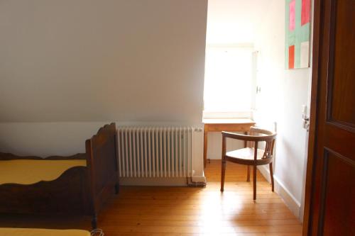 a bedroom with a bed and a chair and a radiator at Villa Beckmann in Gengenbach