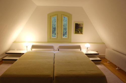 a bedroom with a large bed with two windows at Villa Beckmann in Gengenbach