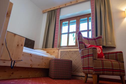 a room with a bed and two chairs and a window at Familienhotel Gasthof Hinteregger in Bad Kleinkirchheim