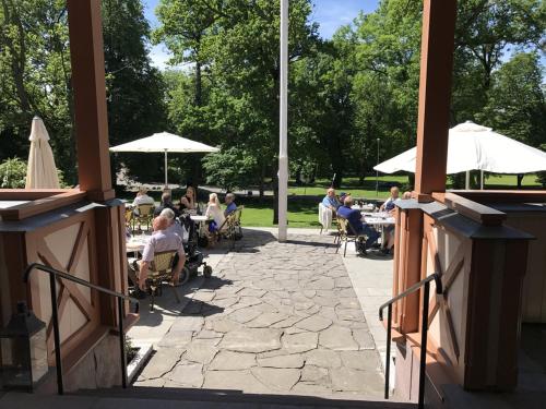 Un groupe de personnes assises à des tables avec des parapluies dans l'établissement Sjømilitære Samfund, à Horten