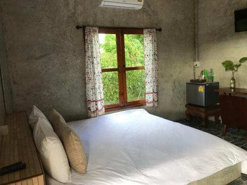 Schlafzimmer mit einem großen Bett und einem Fenster in der Unterkunft บ้านสวนศิริ Siri Garden in Phayao