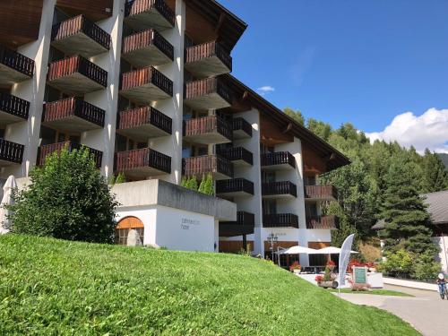 a large building with a grassy hill in front of it at Catrina Hotel in Disentis