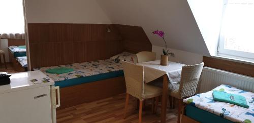 a small room with a bed and a table and chairs at Pension Haus Baron 1 Neckarau in Mannheim