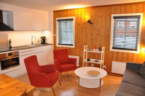 a kitchen and living room with red chairs and a table at Stuga 5 Varmland in Torsby