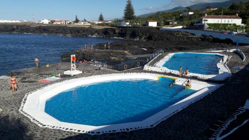 two swimming pools in the water with people in them at Azores Hibiscus House - Mountain and Sea in São Roque do Pico