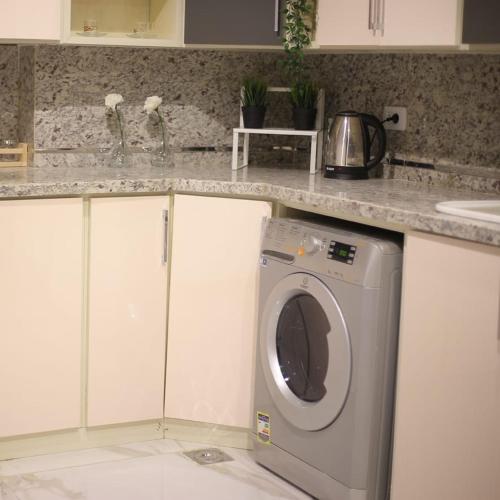a kitchen with a washing machine under a counter at Apartment in Mohandesin (Families Only) in Cairo