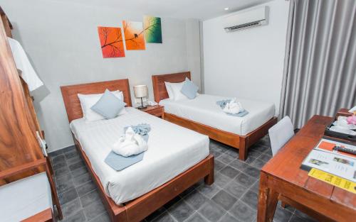 a hotel room with two beds and a desk at Home Chic Hotel in Phnom Penh