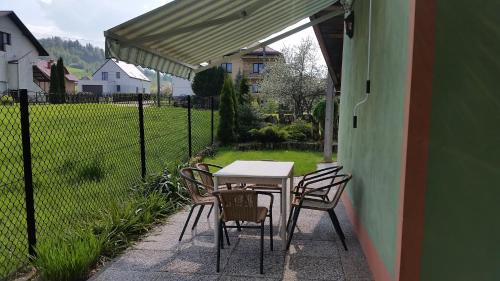 a table and chairs on a patio with a fence at Domek Pod Brzozami in Świnna