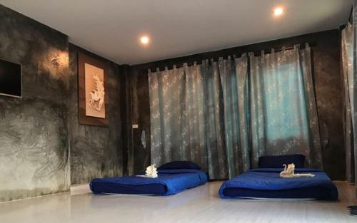 two blue beds in a room with a window at Rai Phusaitran ไร่ภูสายธาร in Mae Taeng