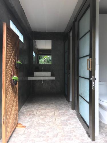 a bathroom with a sink and a toilet and a window at Rai Phusaitran ไร่ภูสายธาร in Mae Taeng