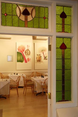 a dining room with tables and chairs and stained glass windows at Quarry Lake Inn in East London