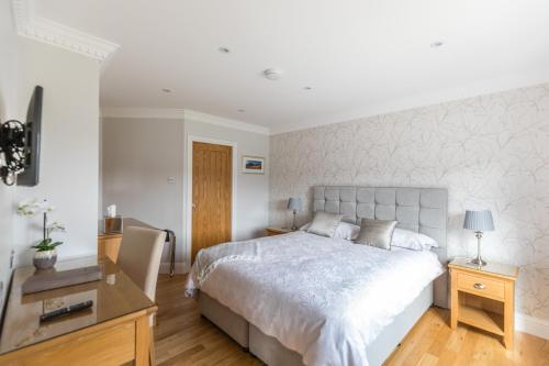 a bedroom with a large white bed and a desk at Woodland View Holiday Apartment in Llanwrda