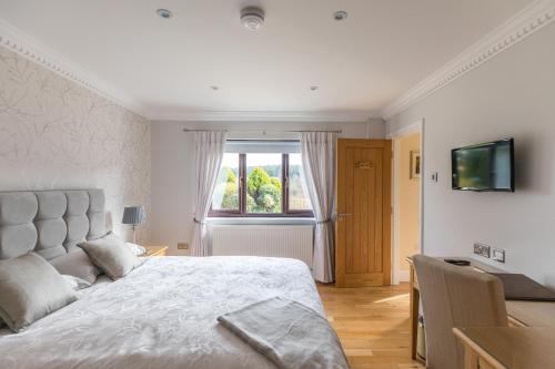 a white bedroom with a bed and a window at Woodland View Holiday Apartment in Llanwrda