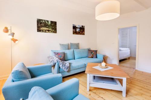 ein Wohnzimmer mit einem blauen Sofa und einem Tisch in der Unterkunft Ferienwohnung Bad Sachsa Harz in Bad Sachsa