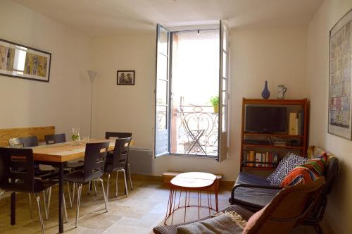 a living room with a table and chairs and a window at Aux 4 FONTAINES in Narbonne