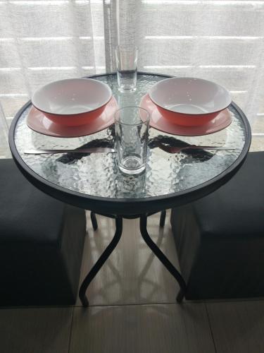 a glass table with two plates and glasses on it at Asia's Beach Apartments in Sattahip