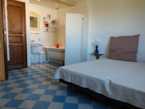 a bedroom with a bed and a bathroom with a tub at La Forge in Signes
