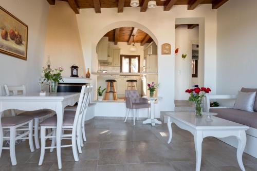a kitchen and living room with white tables and chairs at Cretan Minoan Apartments in Zákros
